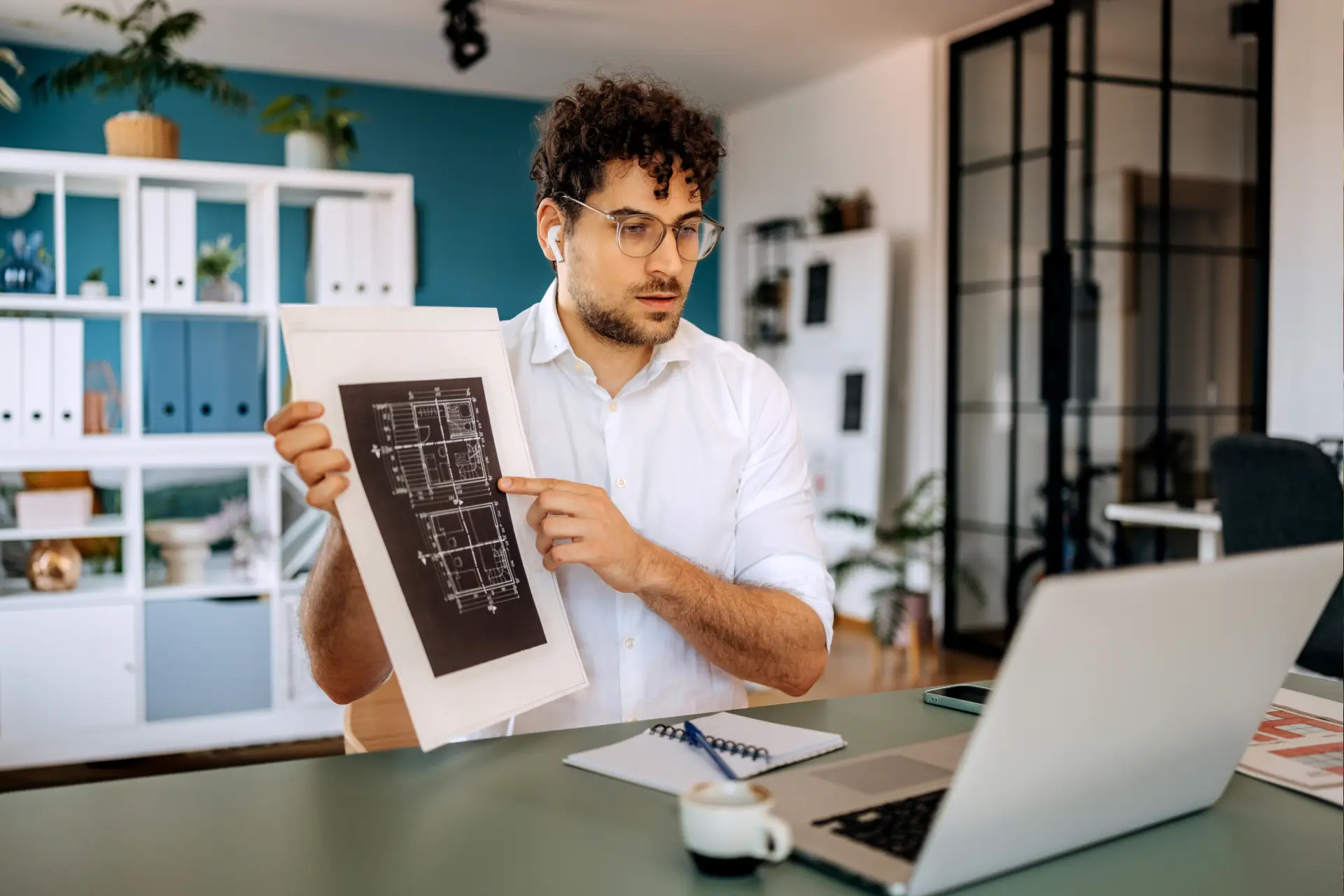 Man presenting architectural plans during video call.