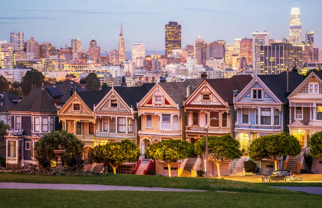 Colorful houses with city skyline at dusk.