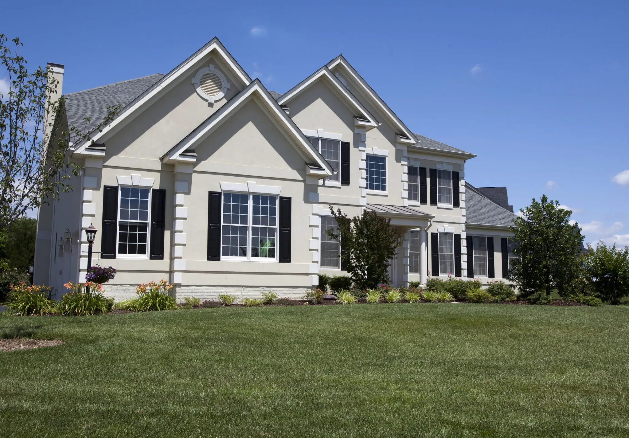 Large suburban house with green lawn.